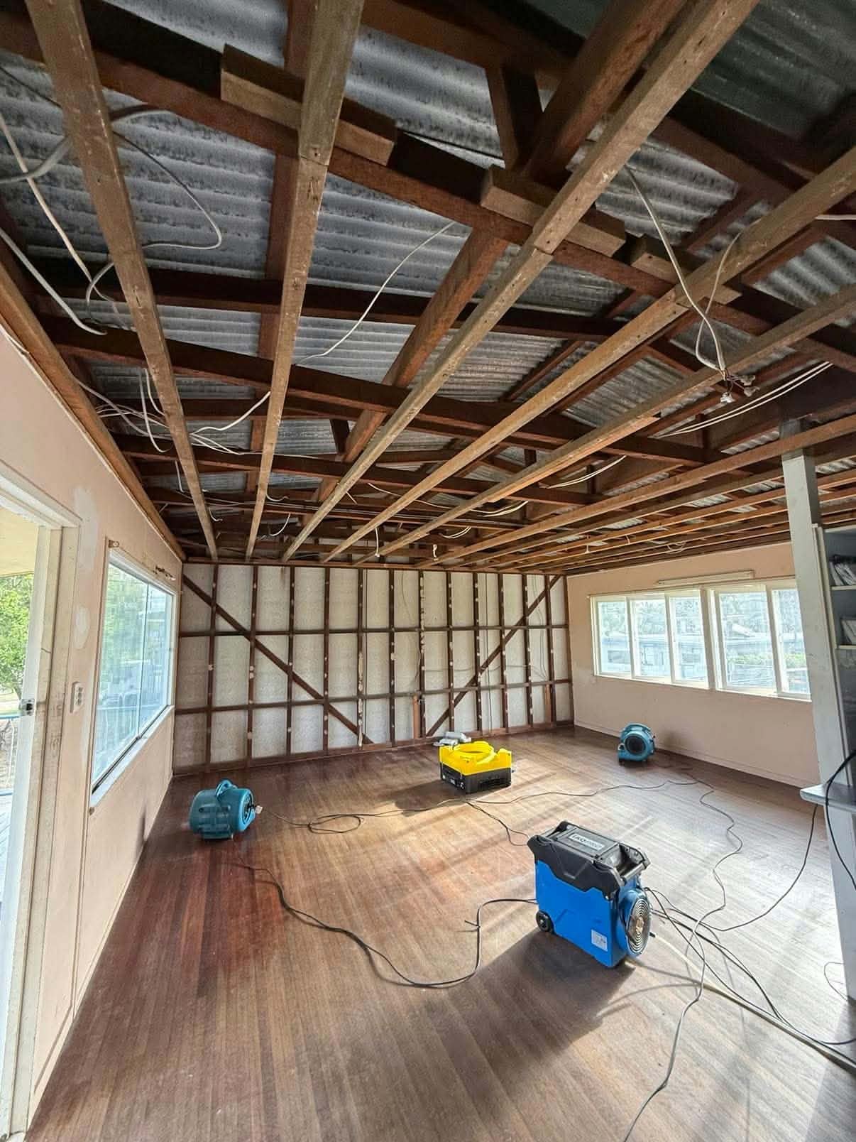 Stripped room with exposed frame and drying equipment before new plasterboard lining