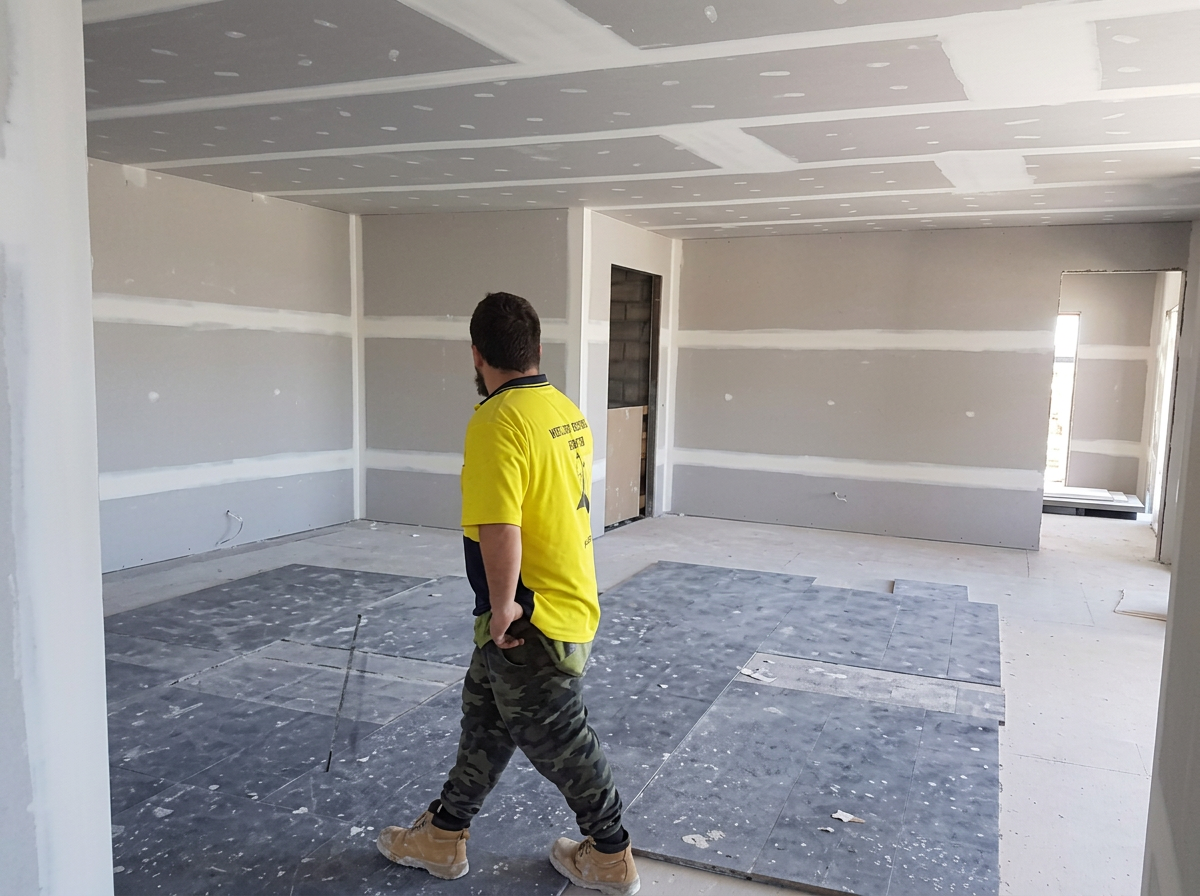 Worker in a room with set plasterboard joints before decorating