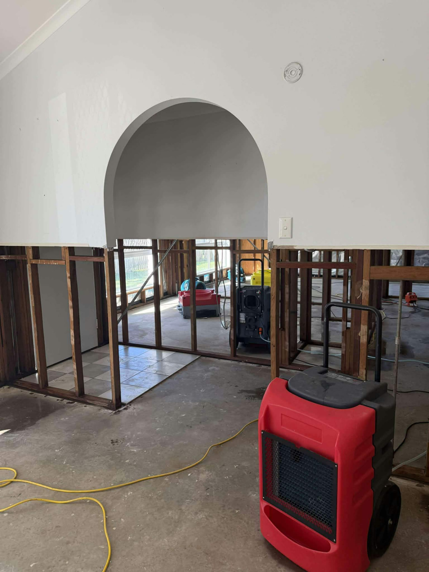 Plasterboard wall cut back to its timber studs with drying equipment running in the room