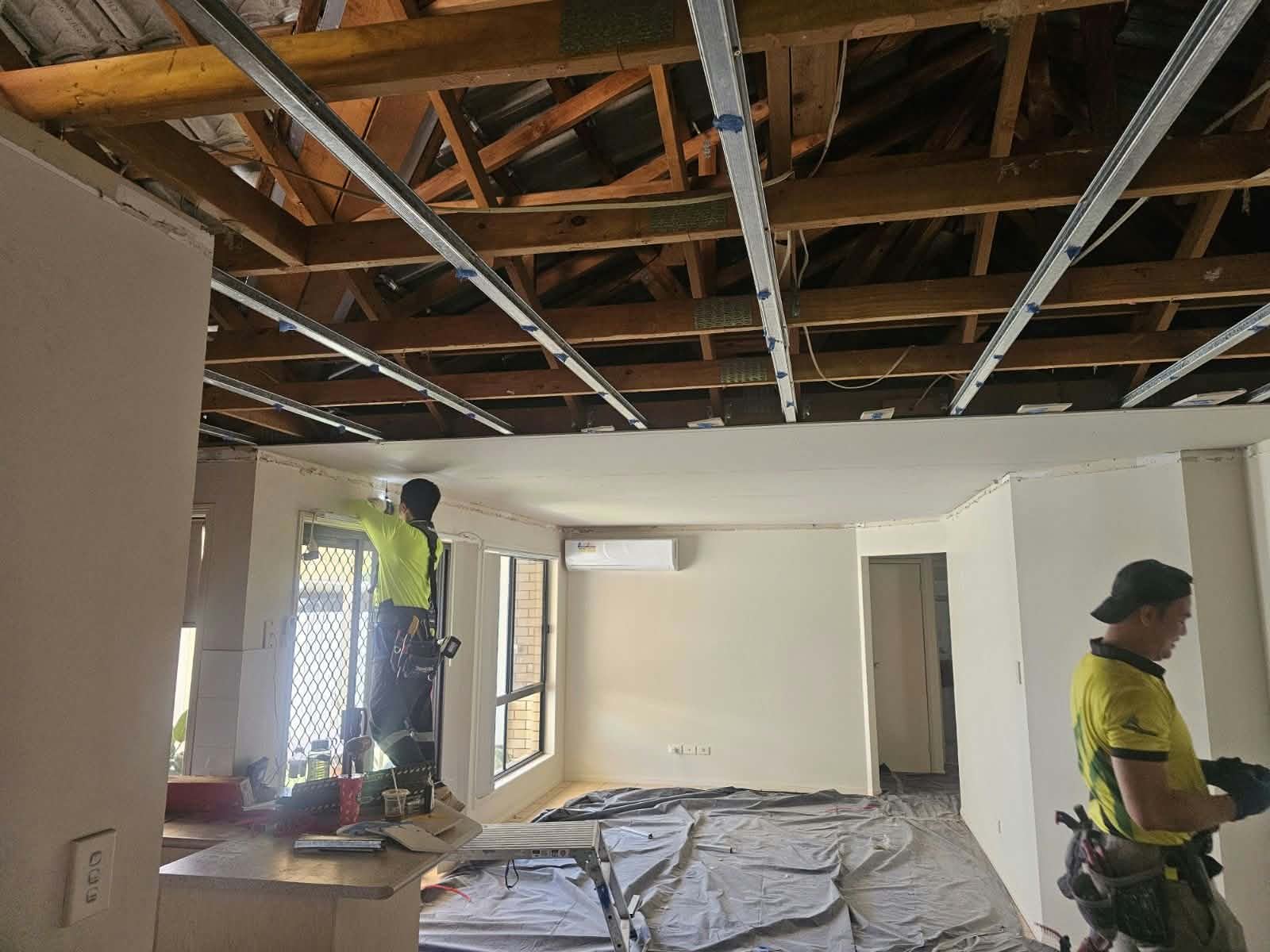 Workers preparing an exposed ceiling frame for new lining
